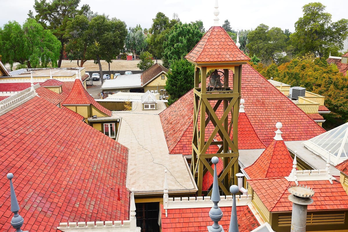The red roofs and wooden bell tower of the Winchester Mystery House seen from above